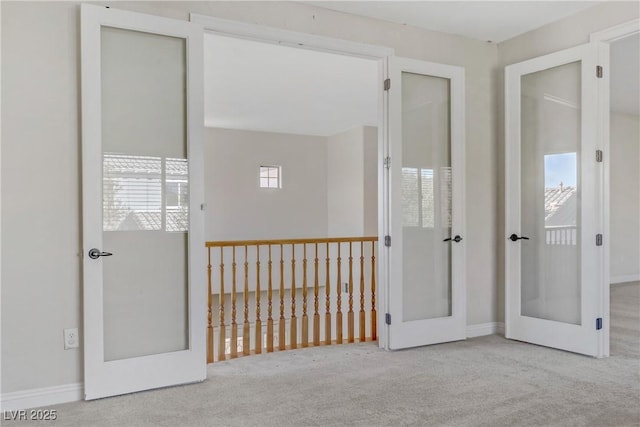 unfurnished room featuring french doors and light colored carpet