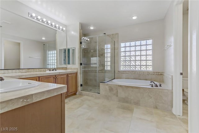 bathroom featuring a garden tub, double vanity, toilet, a sink, and a shower stall