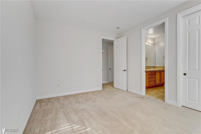 unfurnished bedroom featuring baseboards, light carpet, a sink, and ensuite bath