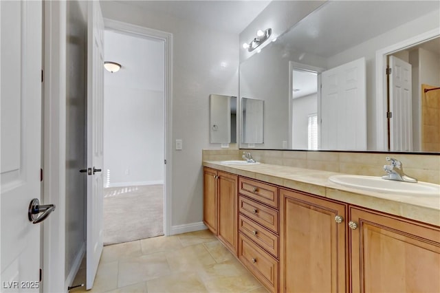 bathroom with tile patterned floors, a sink, baseboards, and double vanity