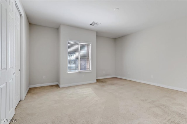 empty room with light colored carpet, visible vents, and baseboards