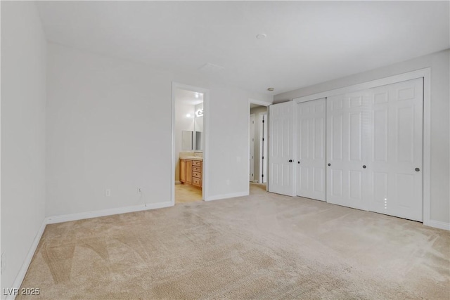 unfurnished bedroom with light carpet, ensuite bath, and baseboards