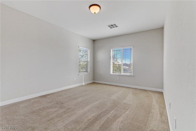 spare room with visible vents, light carpet, and baseboards