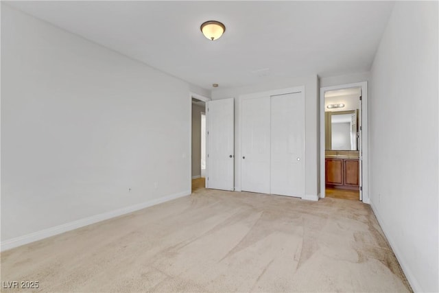 unfurnished bedroom featuring a closet, light colored carpet, connected bathroom, and baseboards