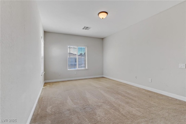 spare room featuring light carpet, visible vents, and baseboards