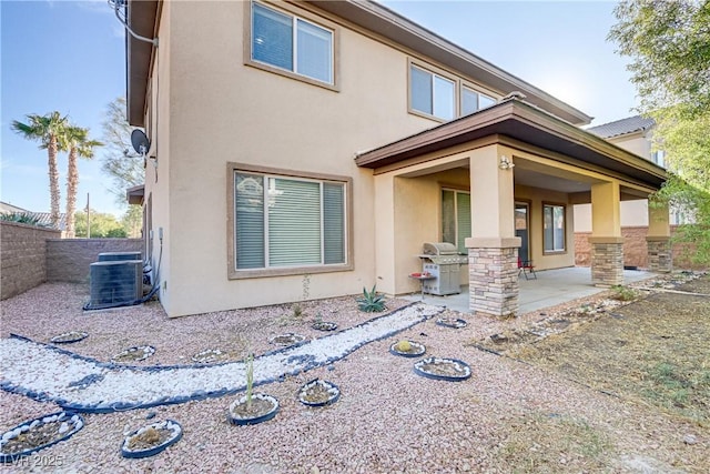 back of property with a fenced backyard, a patio, central AC unit, and stucco siding