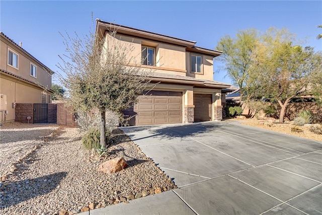 view of front of property with driveway, a garage, stone siding, fence, and stucco siding