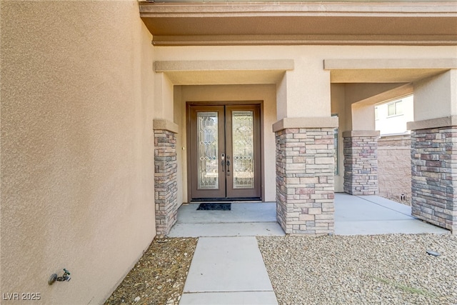 doorway to property with stone siding, french doors, and stucco siding