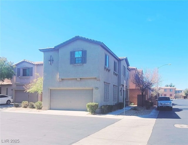 view of front of home with a garage, driveway, a residential view, and stucco siding