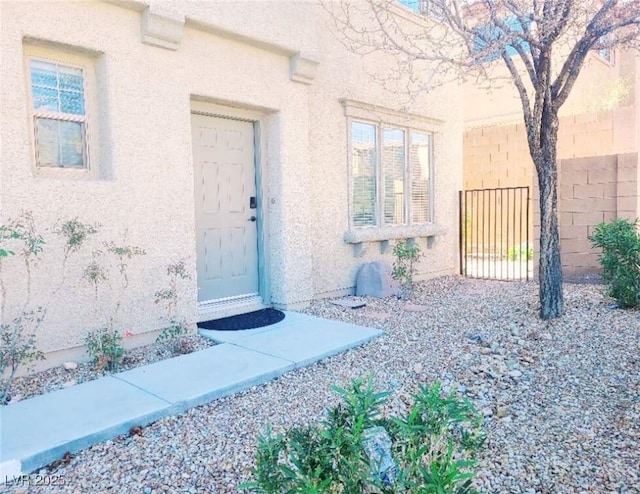 entrance to property with fence and stucco siding