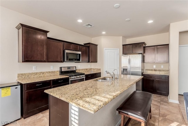 kitchen featuring stainless steel appliances, an island with sink, a sink, and visible vents