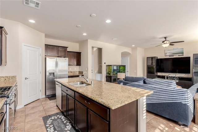 kitchen featuring arched walkways, visible vents, open floor plan, stainless steel appliances, and a sink