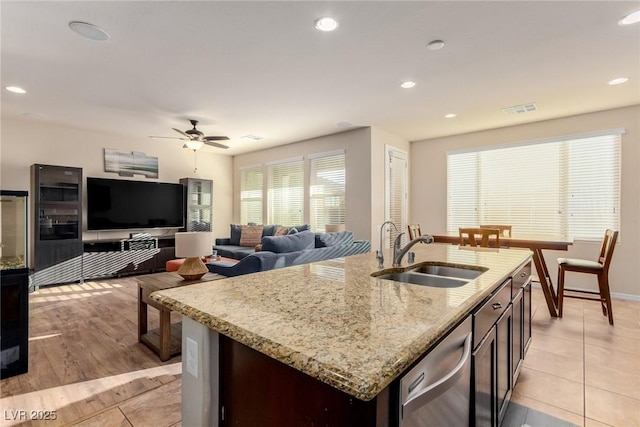 kitchen with visible vents, open floor plan, a kitchen island with sink, a sink, and dishwasher