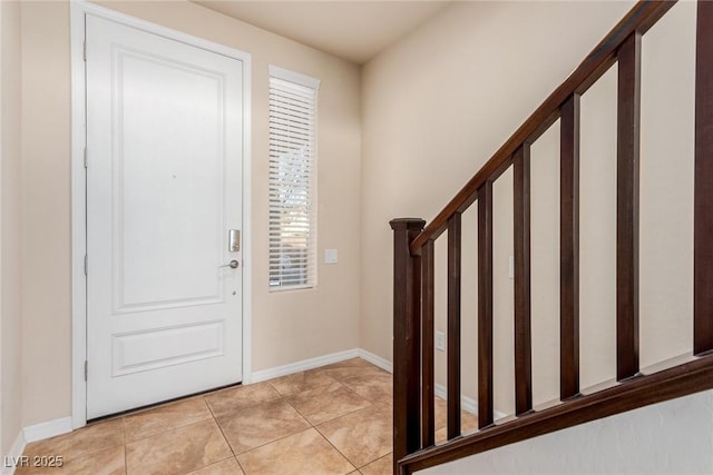 entrance foyer with stairway, light tile patterned flooring, and baseboards