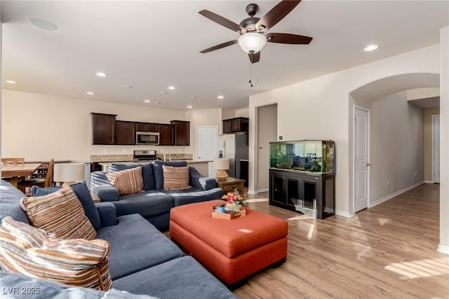 living area featuring light wood-style floors, arched walkways, baseboards, and recessed lighting