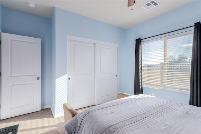 bedroom with ceiling fan, light colored carpet, visible vents, baseboards, and a closet