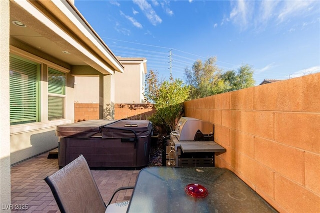 view of patio / terrace with grilling area, a fenced backyard, and a hot tub