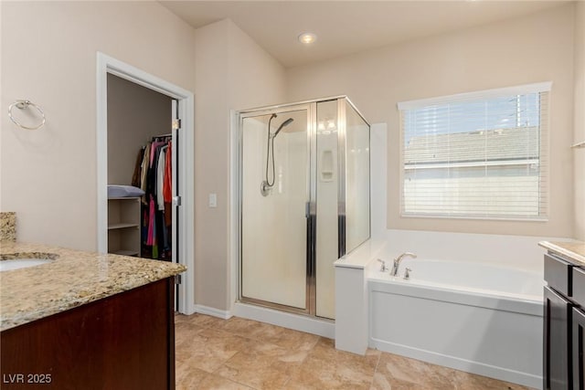 bathroom featuring a stall shower, a walk in closet, vanity, and a bath