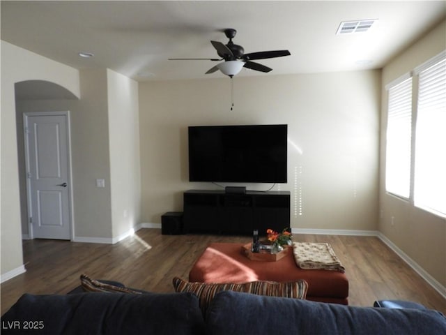 living room featuring baseboards, visible vents, ceiling fan, and wood finished floors