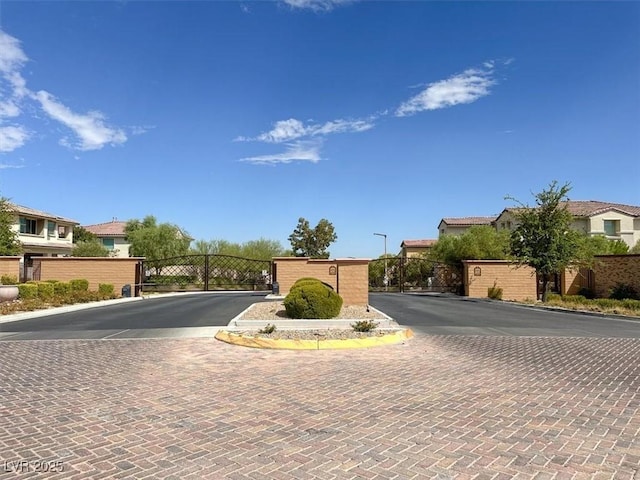 view of street featuring curbs, a gated entry, a residential view, and a gate