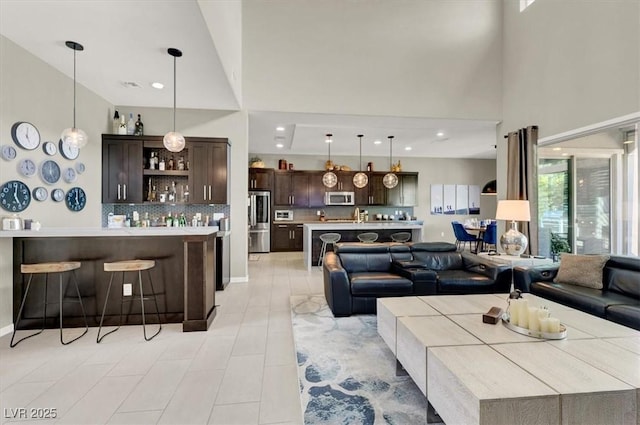 living area featuring light tile patterned floors, recessed lighting, a towering ceiling, and bar