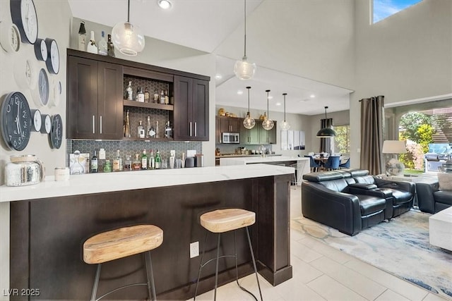 bar featuring decorative light fixtures, recessed lighting, stainless steel microwave, a high ceiling, and decorative backsplash