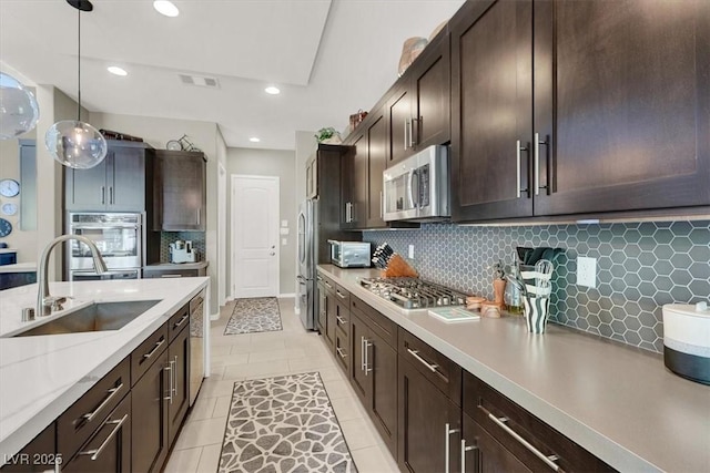 kitchen with dark brown cabinetry, visible vents, stainless steel appliances, pendant lighting, and a sink