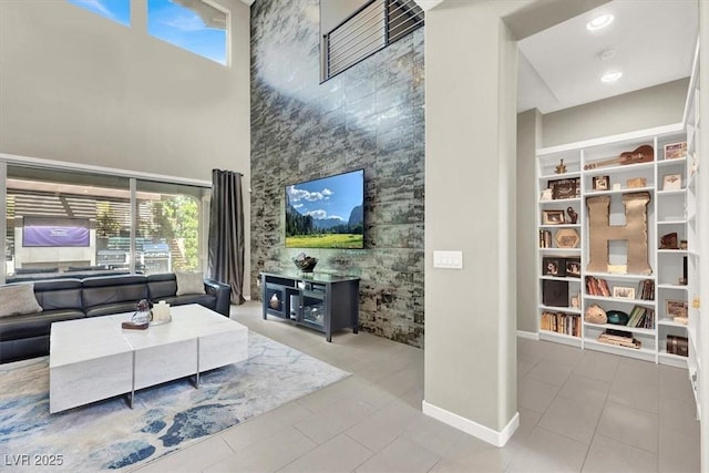 living area with light tile patterned floors, a high ceiling, and recessed lighting