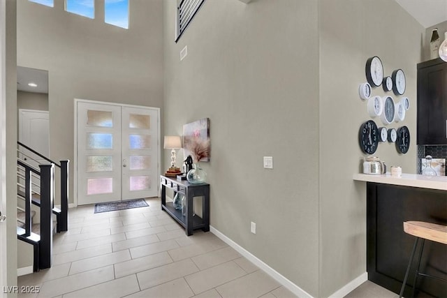 foyer with a high ceiling, visible vents, baseboards, stairs, and french doors