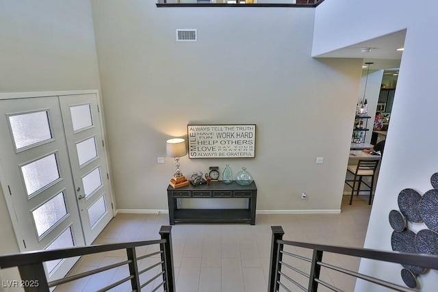 entryway with a towering ceiling, baseboards, visible vents, and french doors