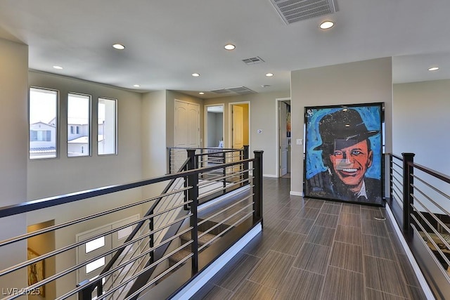 hall featuring recessed lighting, visible vents, and an upstairs landing