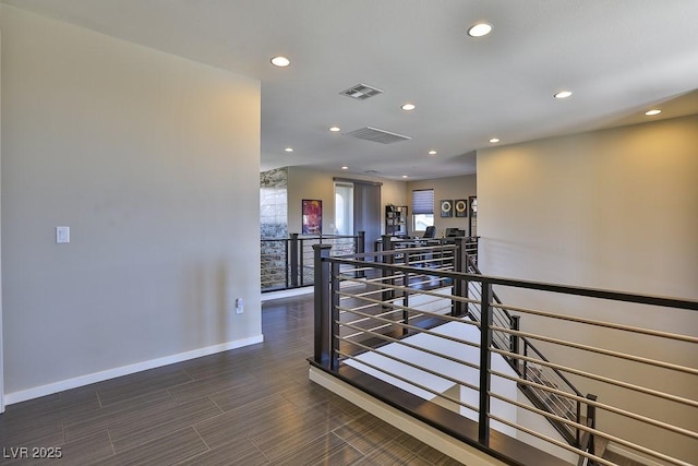 hall featuring recessed lighting, visible vents, and an upstairs landing