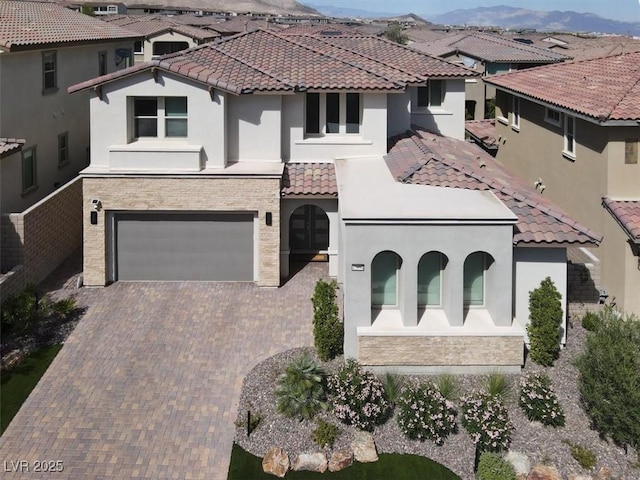 mediterranean / spanish house with decorative driveway, a tile roof, a residential view, and stucco siding