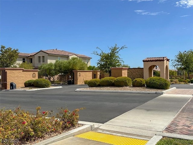 view of road with a residential view, a gate, and curbs