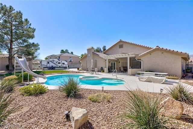 view of pool with a water slide, fence, a pool with connected hot tub, a pergola, and a patio area