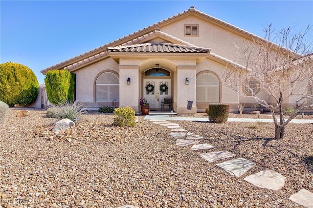 mediterranean / spanish-style home with stucco siding, a tile roof, and french doors