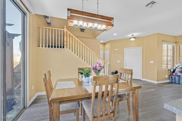 dining room with dark wood-type flooring, visible vents, baseboards, and stairs