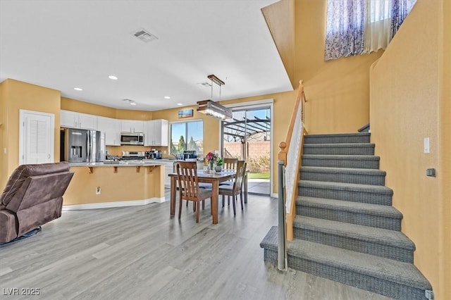 dining space with recessed lighting, visible vents, baseboards, stairs, and light wood-type flooring