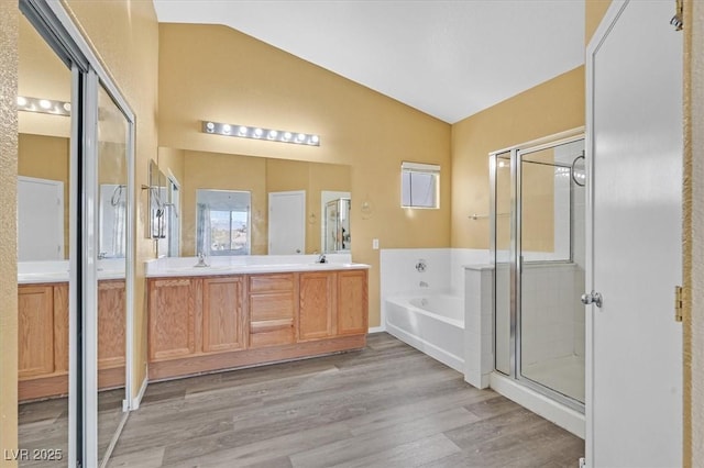 full bathroom with a garden tub, a stall shower, vaulted ceiling, a sink, and wood finished floors