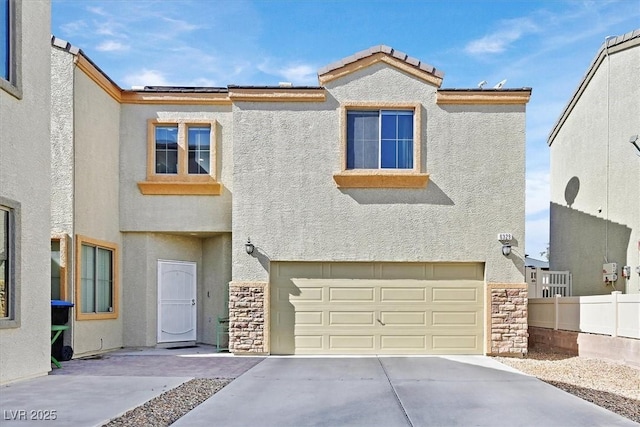 view of front facade with stucco siding, concrete driveway, an attached garage, fence, and stone siding