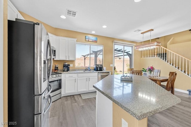 kitchen featuring white cabinets, visible vents, pendant lighting, and stainless steel appliances