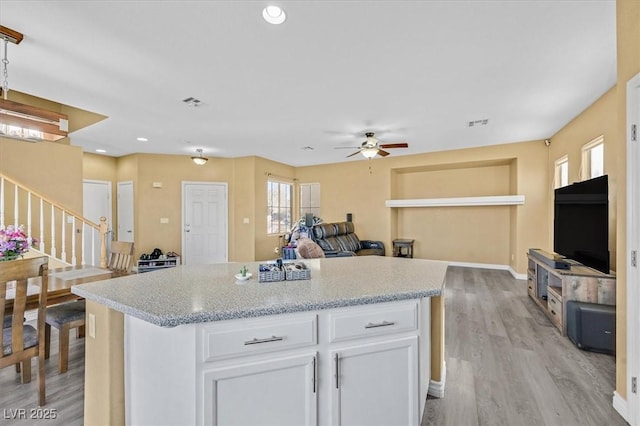 kitchen featuring light wood-type flooring, baseboards, white cabinets, and open floor plan