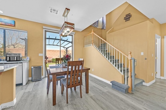 dining space with light wood-style floors, baseboards, stairway, and visible vents