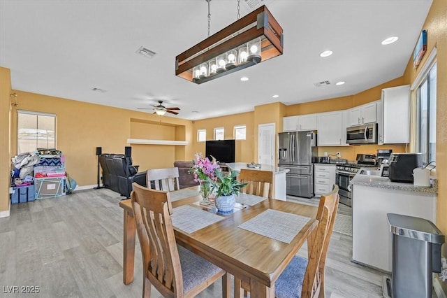 dining area with light wood-type flooring, visible vents, and baseboards