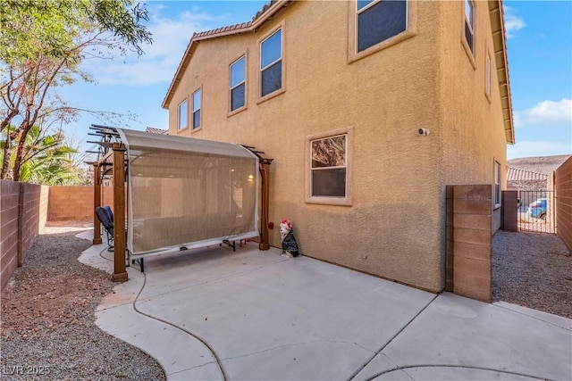 back of house featuring a fenced backyard, a patio, a tiled roof, and stucco siding