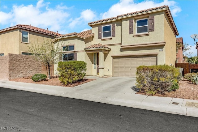 mediterranean / spanish home with a garage, concrete driveway, a tile roof, fence, and stucco siding