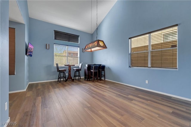 interior space featuring high vaulted ceiling, a dry bar, dark wood-style flooring, and baseboards