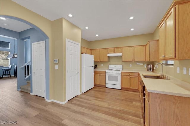 kitchen featuring light brown cabinets, under cabinet range hood, white appliances, a sink, and light countertops