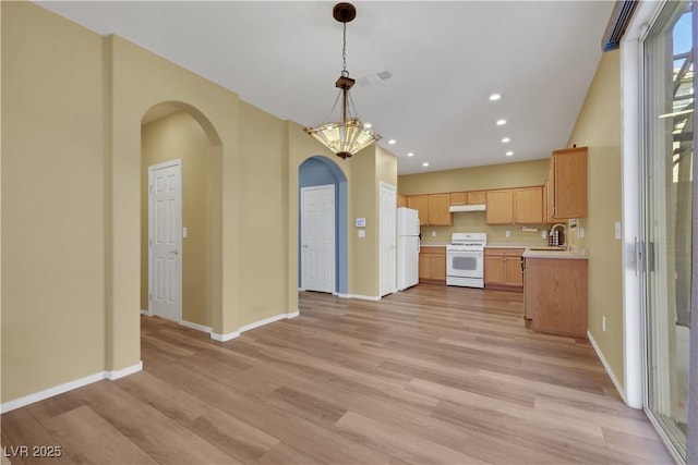 kitchen with white appliances, arched walkways, decorative light fixtures, light countertops, and light wood-style floors