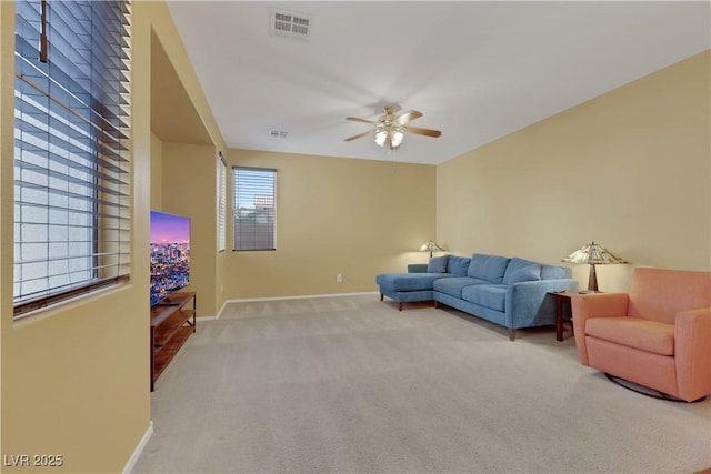 living area with light carpet, a ceiling fan, visible vents, and baseboards